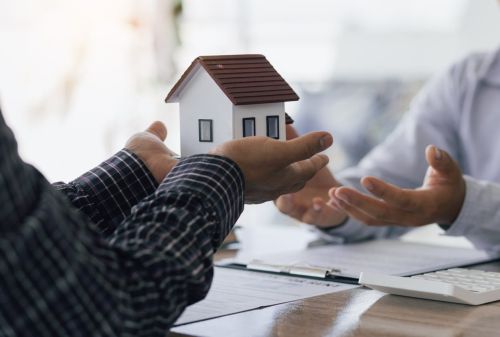 someone holding a small model home in their hands and passing it to someone else - lady bird deed estate planning concept