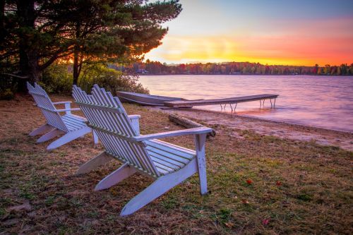 Adirondack Chairs overlooking a beautiful sunset lake on a vacation property.