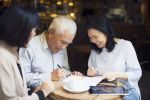 Senior Asian couple signing estate planning document to establish their durable power of attorneys and patient advocate designations.